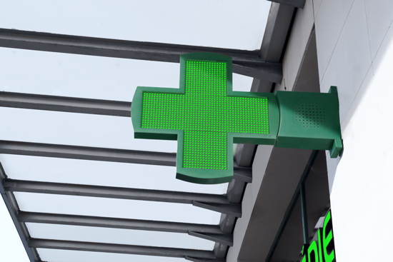 Croix verte lumineuse d'une pharmacie sur fond d'une verrière